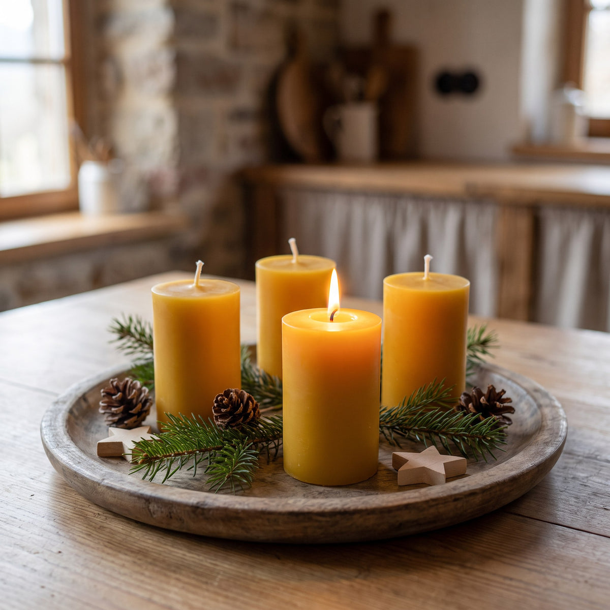 Vier Adventskranz-Kerzen aus Bienenwachs auf einem Holztablett mit Tannenzweigen, Zapfen und Holzsternen, eine Kerze brennt