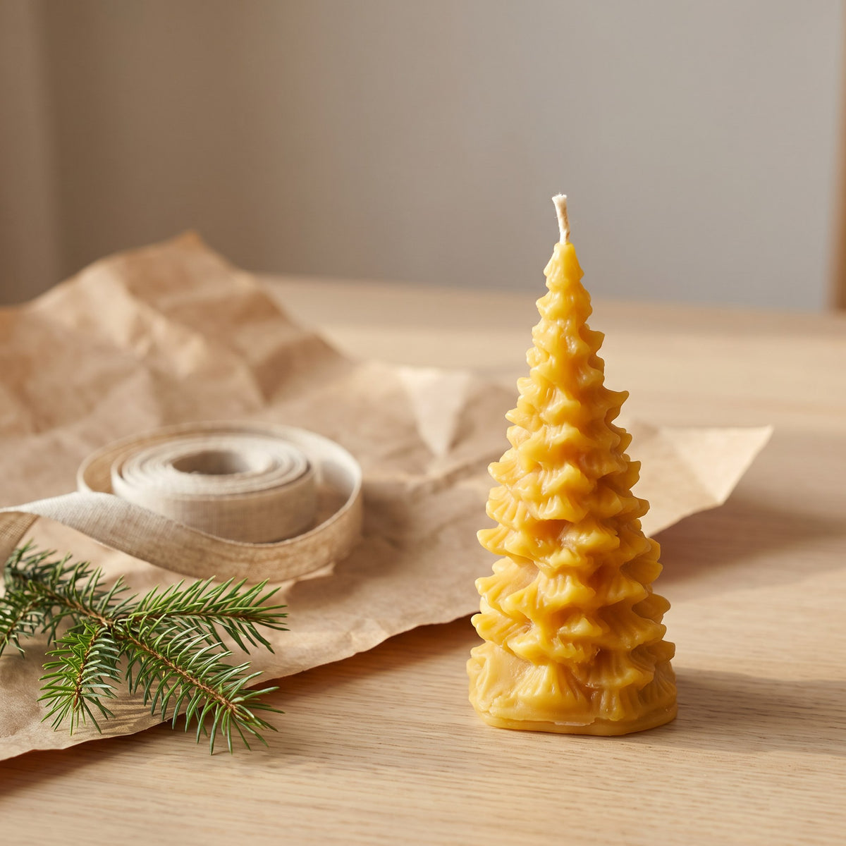 Kleine Tannenbaum-Kerze aus Bienenwachs steht neben Packpapier, Leinenband und Tannenzweig