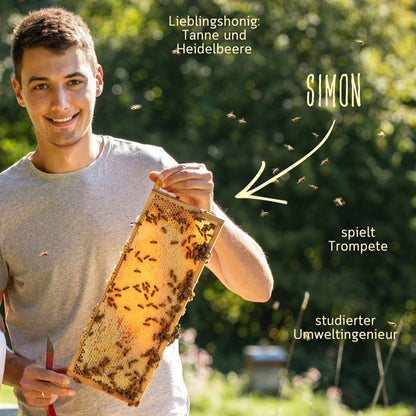 Simon von der Imkerei mit der Goldnote hält eine Honigwabe im Bienenstand im Bayerischen Wald