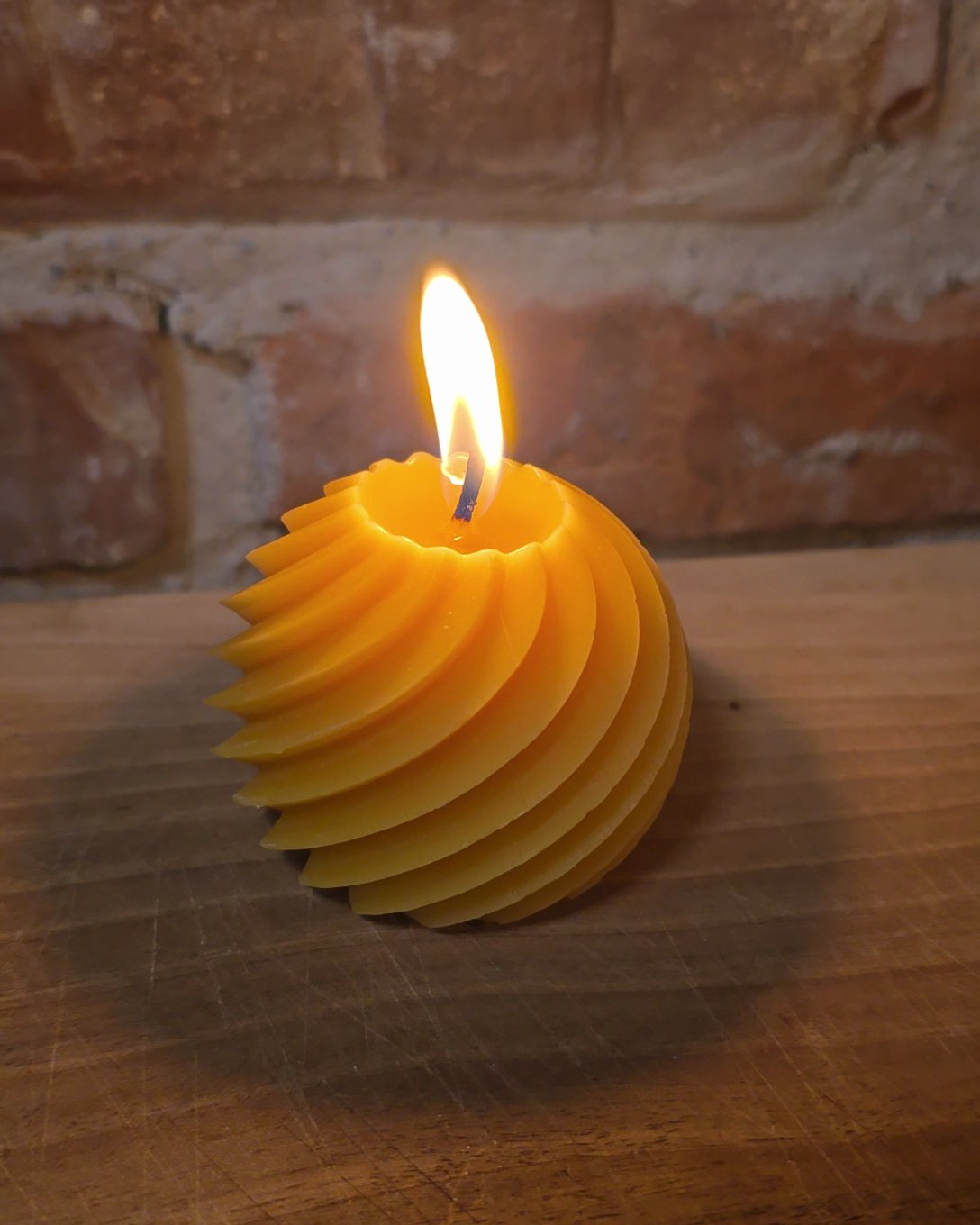 Spiralkugel aus Bienenwachs brennt auf einem Holzbrett