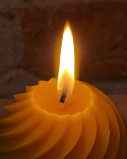 Flamme und Brennteller der Spiralkugel aus Bienenwachs in Nahaufnahme