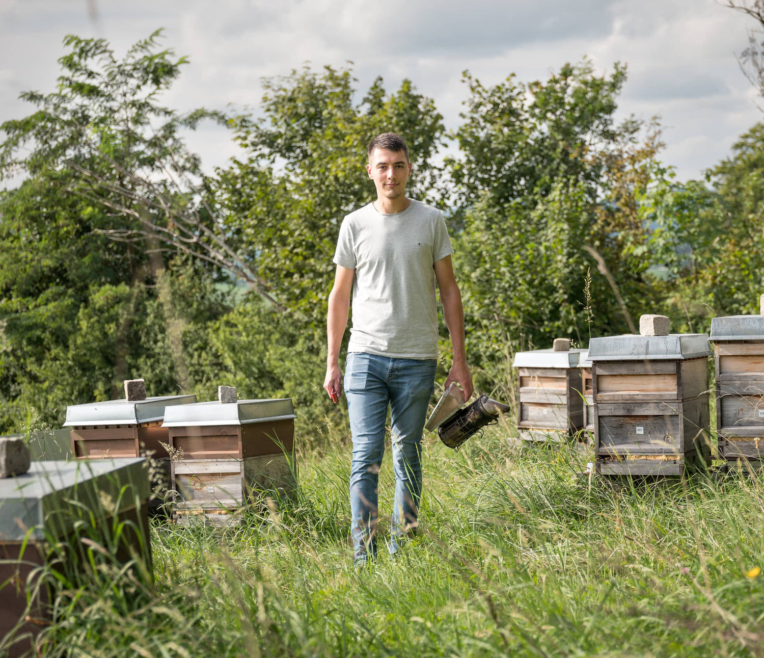 Imker der Imkerei mit der Goldnote bei der Arbeit am Bienenstand zwischen mehreren Bienenvölkern.