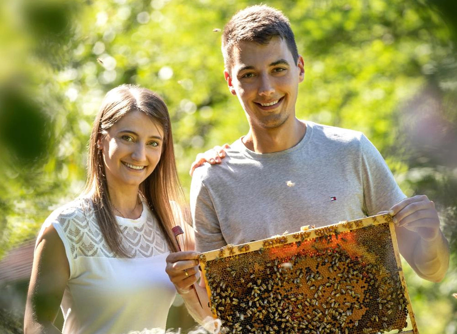 Simon und Stefanie Weber bei der Honigernte mit einer vollen Wabe – Imkerei mit der Goldnote.